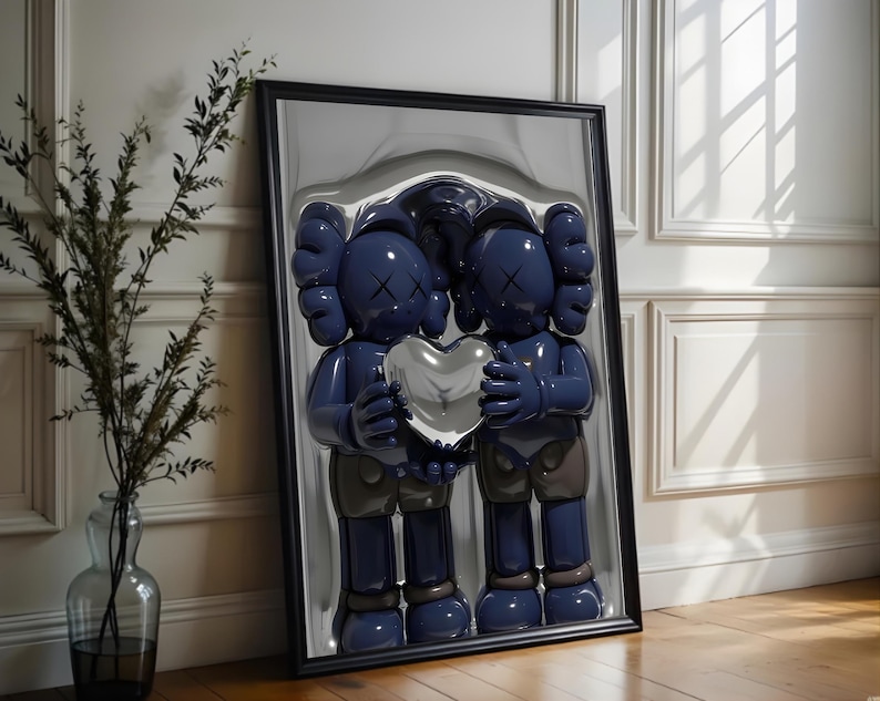 May include: Framed artwork featuring two blue cartoon figures holding a silver heart. The figures have X-shaped eyes and gloved hands. The artwork is in a black frame and leans against a white wall.