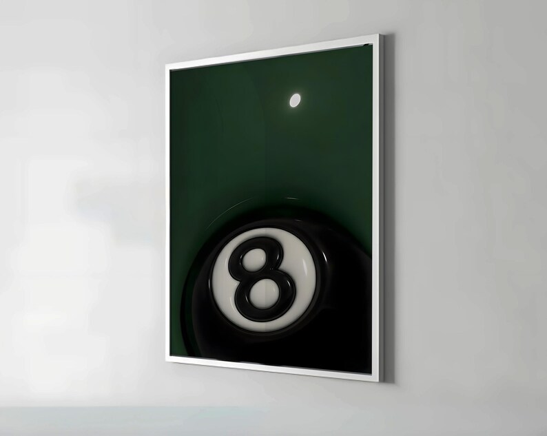 May include: A framed print featuring a close-up of a black and white eight ball. The eight ball is set against a dark green background, with a bright white circle in the upper portion of the image. The print is encased in a white frame.