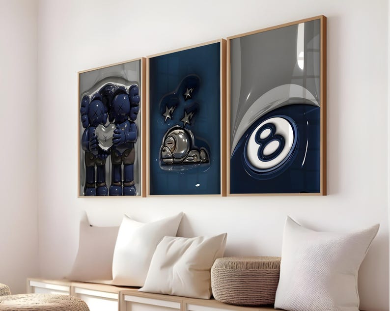 May include: Three framed art prints with a modern design. The prints feature a blue and gray color scheme with abstract figures and a pool ball. The frames are a light brown color.