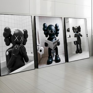 May include: A triptych of framed black and white prints depicting KAWS figures in a bathroom. One figure is in a bath, another reading a newspaper, and the third is reflected in a mirror. The prints are displayed on a light-coloured floor.