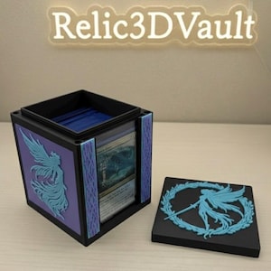 May include: A black and purple card storage box with a removable lid. The box features a blue fairy design on the sides and lid. The text "Relic3DVault" is displayed above the box. The box is designed to hold trading cards.