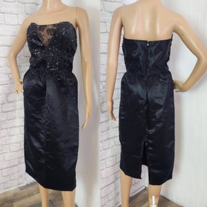 Pode incluir: Um vestido preto sem alças com um corpete de lantejoulas e uma saia de cetim. O vestido tem um corpete justo e uma saia fluida.