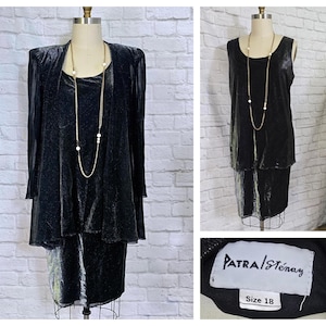 May include: A two-piece black velvet dress set on a mannequin. The set includes a long-sleeved jacket and a sleeveless dress with a layered skirt. A long gold necklace with white beads is draped on the dress. The label reads "PATRA/Stenay" and "Size 18".