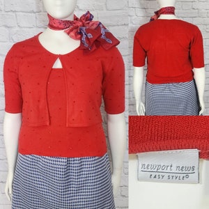 May include: Red knit cardigan with a beaded design and short sleeves. The cardigan is worn over a matching red knit top. The model is also wearing a blue and white houndstooth skirt. The label reads "Newport News Easy Style".
