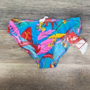 Pode incluir: Uma cueca de banho colorida com um padr&atilde;o de folhas tropicais em tons de azul, rosa, vermelho e amarelo. A cueca tem uma etiqueta que diz "Cole".