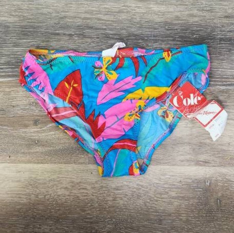 Pode incluir: Uma cueca de banho colorida com um padr&atilde;o de folhas tropicais em tons de azul, rosa, vermelho e amarelo. A cueca tem uma etiqueta que diz "Cole".