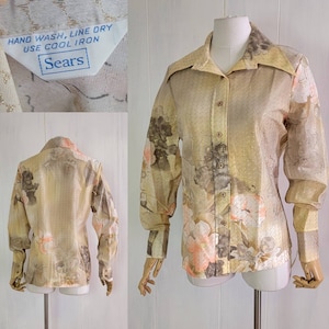 Può includere: Una camicia vintage beige con bottoni, stampa floreale e colletto. La camicia ha maniche lunghe e chiusura con bottoni. L'etichetta riporta "Sears" e "Hand Wash, Line Dry, Use Cool Iron".