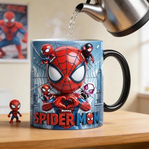 May include: A ceramic Spider-Man mug with a black handle, featuring a 3D Spider-Man design and the words "Spider Mom." The mug is personalized with names and surrounded by a cityscape background. A small Spider-Man figurine is next to the mug.