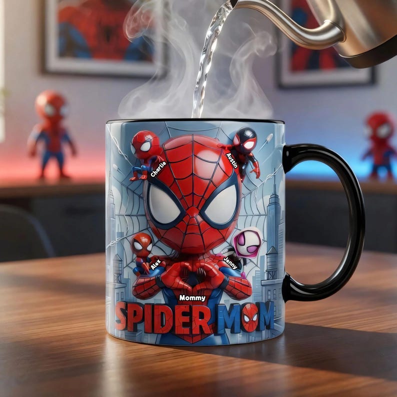 May include: A ceramic mug featuring a Spider-Man design with the words "Mommy Spider Mom". The mug has a black handle and rim, with a blue background and a cityscape design. The mug has the names "Charlie", "Alex", "Austin", and "Jenny".