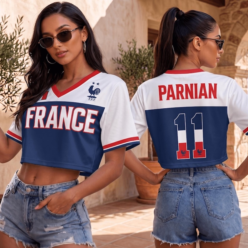 May include: A white and blue cropped V-neck jersey featuring the text FRANCE on the front and PARNIAN 11 on the back. The design includes red trim on the neckline and sleeves, a rooster emblem on the chest, and the French flag colors on the number 11.