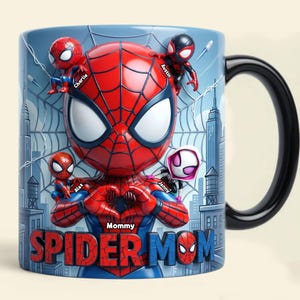 May include: A ceramic mug featuring a Spider-Man design with the words "Spider Mom." The mug has a black handle and a blue background with city buildings. Small Spider-Man figures are positioned around the main character, with names like Charlie, Austin, Alex, and Jenny.