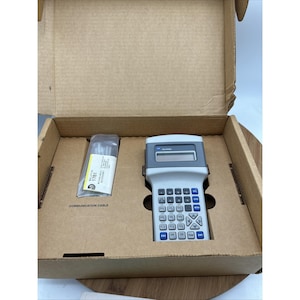 May include: A light gray Allen-Bradley handheld terminal with a dark gray screen bezel and blue and gray buttons, housed in a cardboard box with a plastic-wrapped communication cable labeled Bulletin 1761 MicroLogix Accessory.