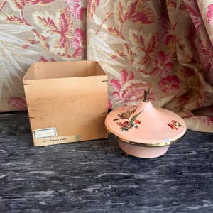 Portacipria musicale/portaoggetti da toeletta floreale color rosa atomico degli anni '50 con frammento di scatola originale.