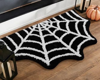 May include: A black and white rug shaped like a spider web. The rug features a high-contrast design with a central point from which white web lines radiate outward toward the edges, creating a distinct, irregular, and organic web-like silhouette.