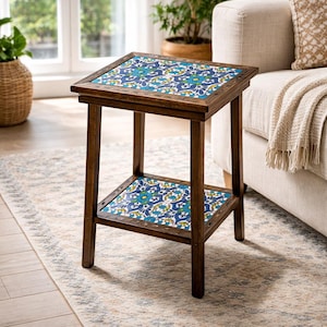 May include: A small, square side table with a dark wood frame. The tabletop and lower shelf feature a blue and white patterned tile design. The table is 24 inches tall and 18 inches wide.