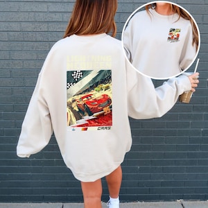 Puede incluir: Sudadera color crema con un dise&ntilde;o de Rayo McQueen de la pel&iacute;cula Cars. El dise&ntilde;o incluye el n&uacute;mero 95, una bandera a cuadros y la palabra "CARS". Una versi&oacute;n m&aacute;s peque&ntilde;a del dise&ntilde;o est&aacute; en la parte delantera.