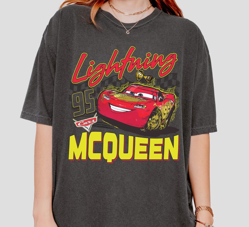 Puede incluir: Camiseta gris oscuro con un dise&ntilde;o de Rayo McQueen de la pel&iacute;cula Cars. El dise&ntilde;o incluye los textos "Lightning", "95" y "McQueen" en amarillo y rojo.