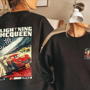 Puede incluir: Sudadera negra con un gr&aacute;fico de Rayo McQueen de la pel&iacute;cula Cars. La parte trasera muestra una escena de carreras con el n&uacute;mero 95. La parte delantera tiene el n&uacute;mero 95 y el nombre de Rayo McQueen.