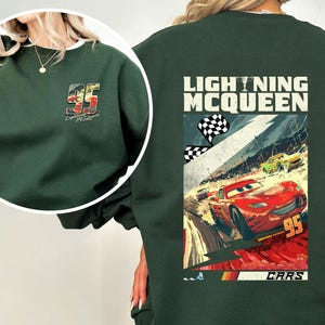 Puede incluir: Sudadera verde oscuro con un gr&aacute;fico de Rayo McQueen de la pel&iacute;cula Cars. La parte trasera muestra una escena de carreras con "LIGHTNING MCQUEEN" y "CARS". El pecho izquierdo tiene un gr&aacute;fico m&aacute;s peque&ntilde;o del n&uacute;mero 95.