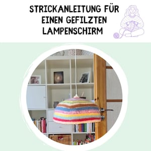 Puede incluir: Una pantalla de lámpara a rayas multicolores cuelga del techo. La pantalla está hecha de hilo de varios colores, incluyendo rojo, azul, amarillo y marrón. El texto en la parte superior dice "STRICKANLEITUNG FÜR EINEN GEFILZTEN LAMPENSCHIRM".
