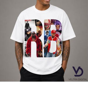 Puede incluir: Camiseta blanca con las letras "RB" formadas por un collage de im&aacute;genes de m&uacute;sicos. El dise&ntilde;o incluye fotos de Usher, Kanye West y Chris Brown. El texto "US" y "STAND" tambi&eacute;n es visible.
