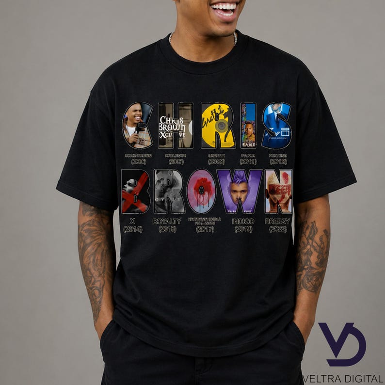 Puede incluir: Camiseta negra con el nombre "CHRIS BROWN" en un dise&ntilde;o colorido y estilizado. El dise&ntilde;o incorpora portadas de &aacute;lbumes y t&iacute;tulos, incluyendo "X", "Royalty" e "Indigo". La camiseta tiene cuello redondo y mangas cortas.