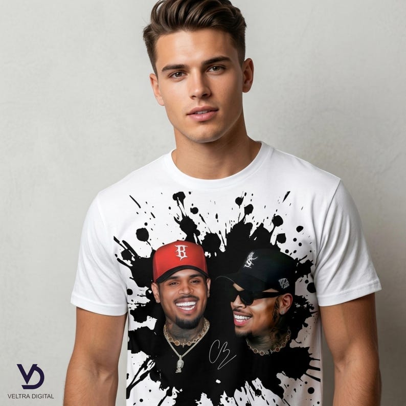Puede incluir: Camiseta blanca con un dise&ntilde;o de salpicaduras de tinta negra y dos retratos de un hombre sonriente con una gorra de b&eacute;isbol roja y una gorra de b&eacute;isbol negra. La camiseta tiene la firma "CB".