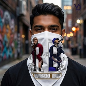 Puede incluir: Cubierta facial blanca con im&aacute;genes de dos m&uacute;sicos con micr&oacute;fonos. El dise&ntilde;o incluye las letras "R & B", las palabras "THE TOUR" y "RAYMOND & BROWN". La cubierta facial est&aacute; siendo usada.