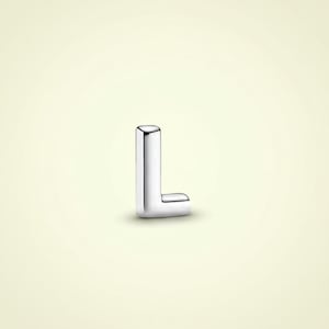 Può includere: Una lettera "L" argentata e lucida, isolata su uno sfondo giallo chiaro. La lettera maiuscola è tridimensionale con bordi arrotondati, che riflettono la luce. La lettera è un singolo pezzo di metallo, probabilmente un gioiello o un oggetto decorativo.