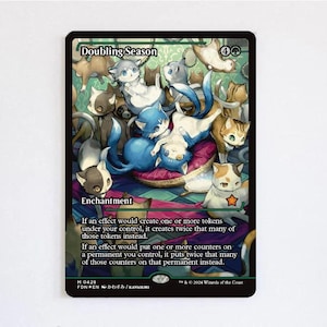 May include: A Doubling Season trading card featuring an illustration of numerous cats in various colors and poses. The card text reads Enchantment, and details the effect of doubling tokens and counters. The border is black with green accents.
