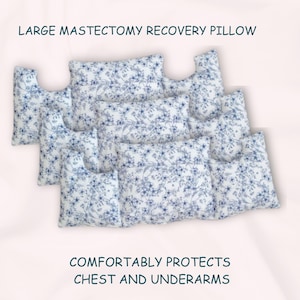 May include: A large white and blue floral print recovery pillow with a cutout for the arms. The pillow is designed to comfortably protect the chest and underarms.  LARGE MASTECTOMY RECOVERY PILLOW. COMFORTABLY PROTECTS CHEST AND UNDERARMS.