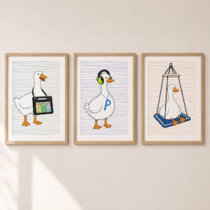 May include: Three framed wall art prints featuring white ducks with orange beaks and feet. The first duck carries a black tablet, the second wears green headphones and a blue letter P necklace, and the third sits on a blue hanging swing.