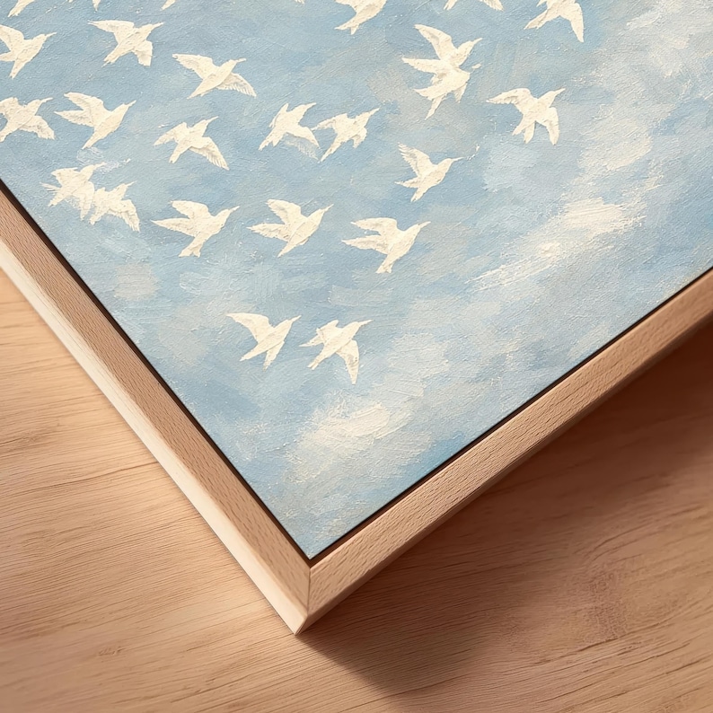 May include: A framed painting featuring white birds in flight against a light blue sky with white cloud accents. The artwork has a natural wood frame, adding a touch of warmth to the piece. The painting is a decorative item.