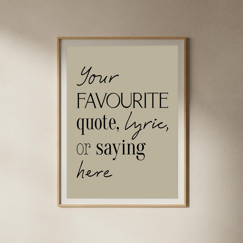 Pu&ograve; includere: Stampa incorniciata con il testo "Your FAVOURITE quote, lyric, or saying here" in corsivo nero. Lo sfondo &egrave; beige chiaro e la cornice &egrave; color legno chiaro.