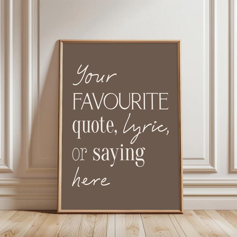 Pu&ograve; includere: Una stampa incorniciata con sfondo marrone e la scritta "Your FAVOURITE quote, lyric, or saying here" in bianco, con un carattere elegante. La cornice &egrave; di colore marrone chiaro e la stampa &egrave; esposta su una parete bianca e un pavimento in legno.