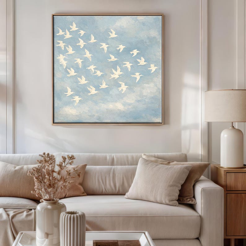 Framed canvas print of a flock of white birds in free flight against a soft powder-blue textured sky, painted in an oil-painting style with visible brushwork. Peaceful birds in flight wall art for nursery, bedroom, or minimalist living room décor — cream and sky blue palette, ready to hang.