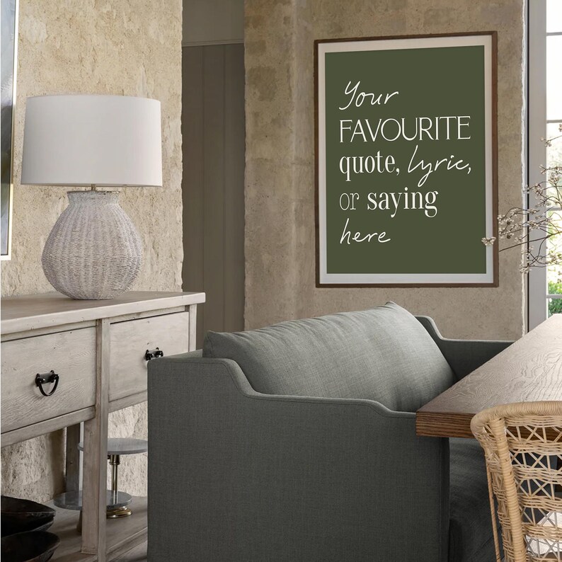 Pu&ograve; includere: Un salotto con una lampada in vimini bianca su un mobile in legno chiaro. Una stampa incorniciata con il testo "Your FAVOURITE quote, lyric, or saying here" &egrave; appesa al muro. Una poltrona grigia e un tavolo di legno sono visibili.