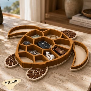 Può includere: Un vassoio organizer a forma di tartaruga con cornice marrone e base beige, dotato di molteplici scomparti esagonali per piccoli oggetti. Il vassoio contiene una chiave dell'auto, un anello, auricolari bianchi, monete e una banconota.