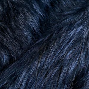 Puede incluir: Primer plano de una tela de piel sintética azul marino. La tela tiene fibras largas y suaves con un ligero brillo, creando una textura lujosa. El color varía ligeramente, con tonos más oscuros y claros de azul.