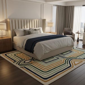 May include: A bedroom with a large bed, nightstands, and a patterned rug. The bed has a tall, upholstered headboard and is covered with white linens and a navy blue throw. The rug features geometric patterns in green, gold, and navy.