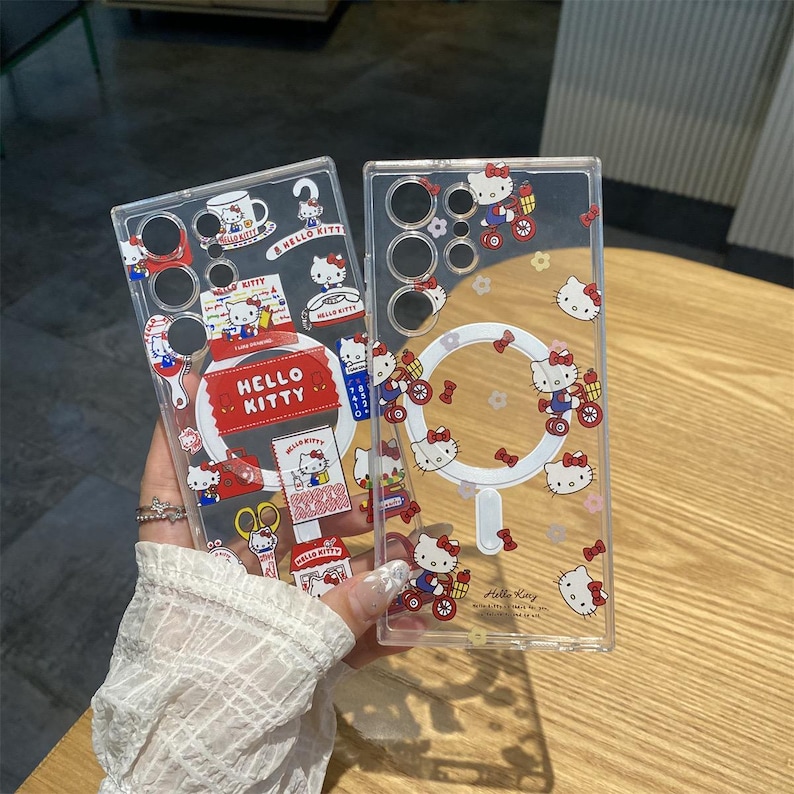 May include: Clear phone cases featuring Hello Kitty designs. One case has a large Hello Kitty label and various themed stickers. The other case has Hello Kitty riding a bicycle and other Hello Kitty graphics. Both cases are transparent.
