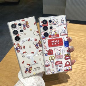 May include: Two clear phone cases with Hello Kitty designs. One case features Hello Kitty riding a bicycle, the other has various Hello Kitty stickers. The cases are for a Samsung phone.