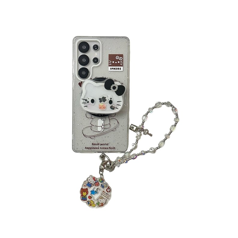 Puede incluir: Una funda transparente para tel&eacute;fono con un fondo brillante, con un dise&ntilde;o de Hello Kitty blanco con un lazo negro y un agarre emergente. La funda tiene un charm a juego con personajes de dibujos animados coloridos y una cadena de cuentas.