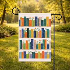 May include: A rectangular garden flag featuring a colorful bookshelf design. The flag displays three rows of illustrated books in various colors, with floral accents. The books are arranged on white shelves, creating a whimsical and decorative outdoor accent.