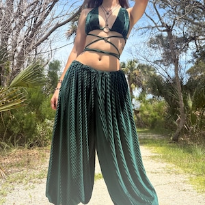 May include: A dark green two-piece set consisting of a pleated halter top with a central ring and wrap-around waist ties, paired with matching wide-leg pleated trousers featuring an elasticized waistband and a loose, flowing silhouette.
