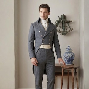Könnte beinhalten: Ein grauer Zweireiher-Anzug mit hohem Kragen und goldenen Knöpfen. Der Anzug umfasst eine lange Jacke mit Schößen und eine passende Hose. Ein weißes Hemd und ein cremefarbener Gürtel werden darunter getragen. Der Anzug ist formelle Kleidung.