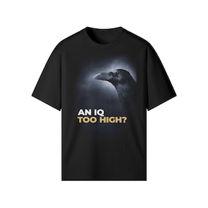 以下が含まれることがあります： 黒いTシャツ。暗く煙のような背景にカラスの頭のイラストが描かれています。「AN IQ TOO HIGH？」の文字が金色でプリントされています。カジュアルな半袖Tシャツです。