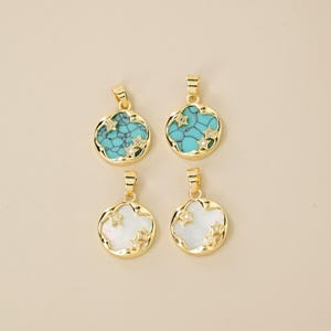May include: Four gold-colored pendants with round shapes. Two pendants feature a turquoise stone with star-shaped accents, and the other two have a white stone with star-shaped accents. The pendants are displayed on a light beige background.