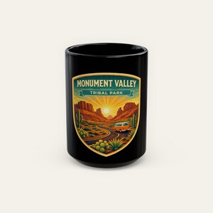 May include: Black ceramic mug featuring a colorful illustration of Monument Valley Tribal Park. The design includes a road, a van, cacti, and the text "Monument Valley Tribal Park" in a green and gold banner.
