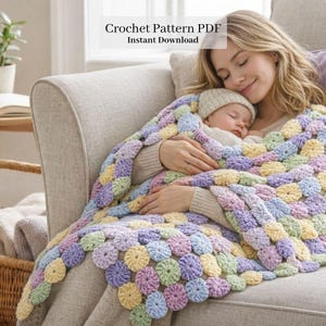 Peut inclure: Une couverture au crochet aux couleurs pastel avec un motif floral, drapée sur une personne tenant un bébé endormi. La couverture présente un mélange de teintes jaunes, vertes, bleues et violettes. Le texte de l'image indique "Crochet Pattern PDF Instant Download."